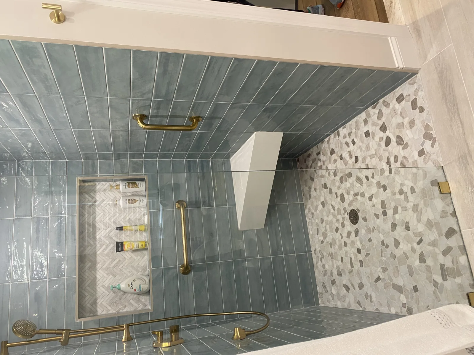 Shower with blue tile walls and brushed gold fixtures