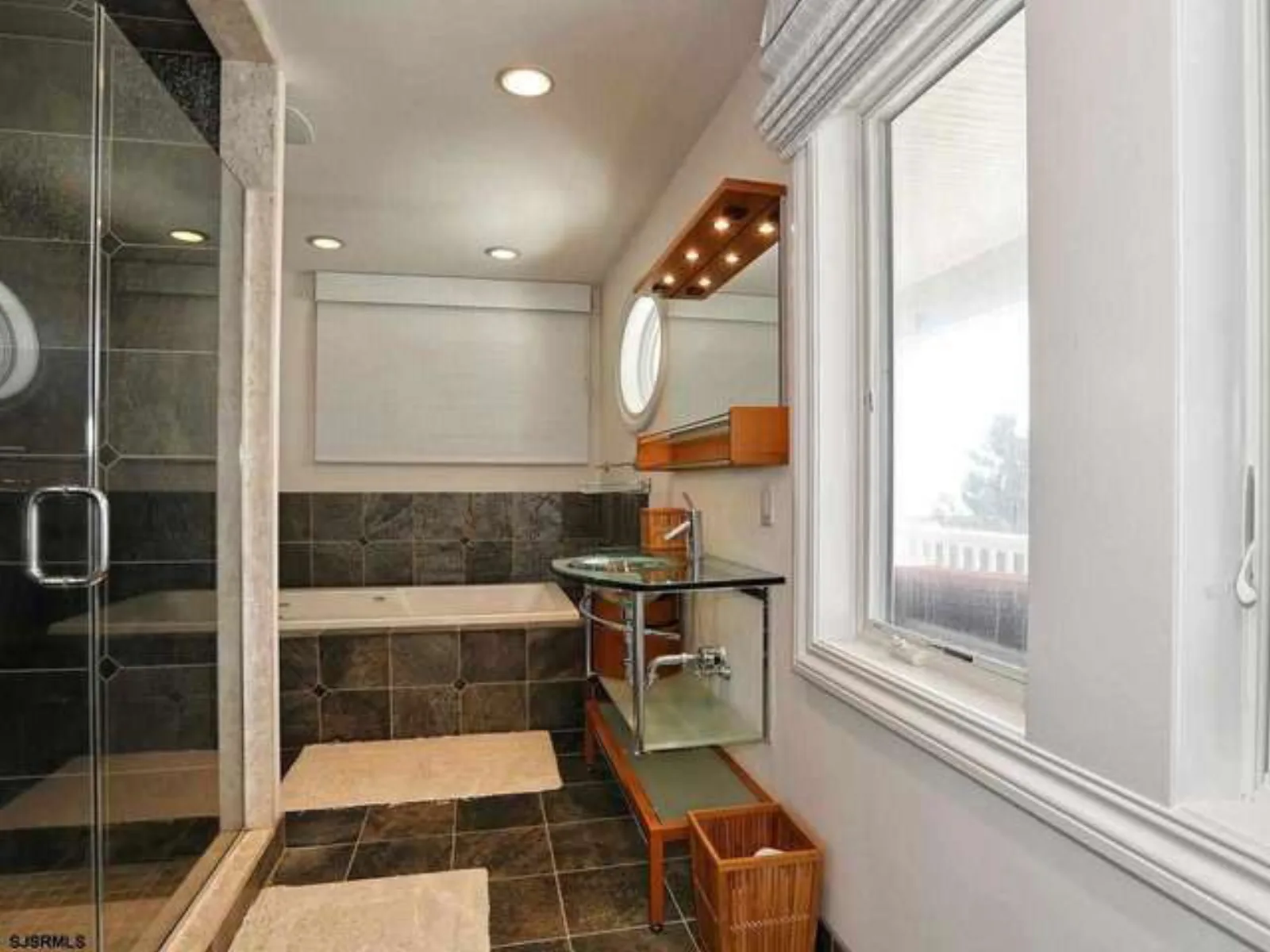 Glass shower with slate tile walls and a bench