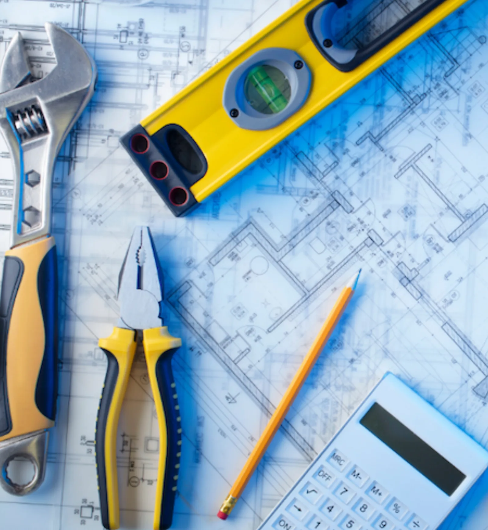 Contractor tools and a level laid over blueprints
