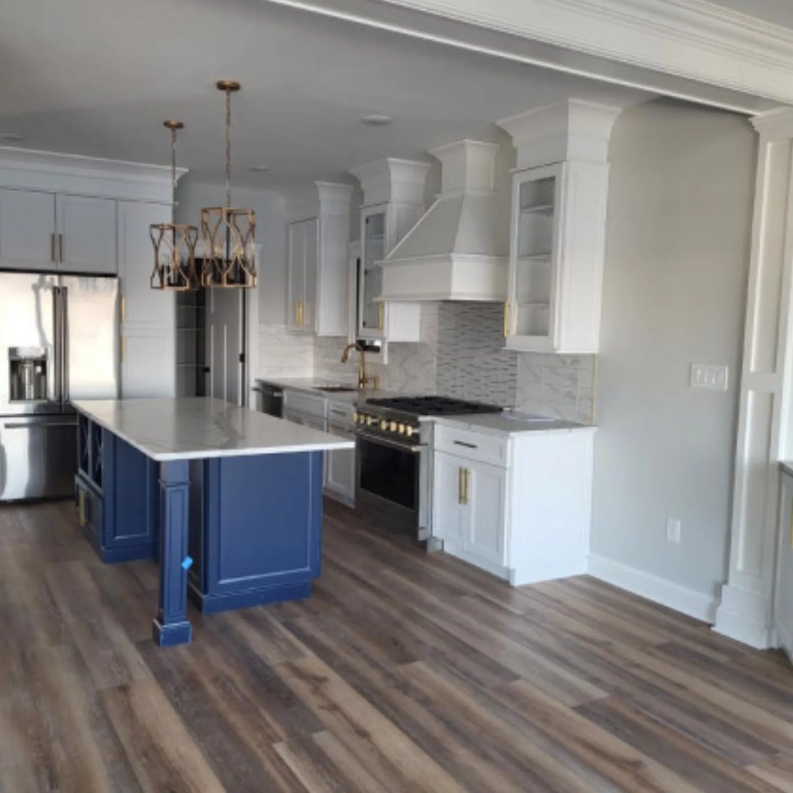 Navy island under a tiered chandelier with white cabinetry