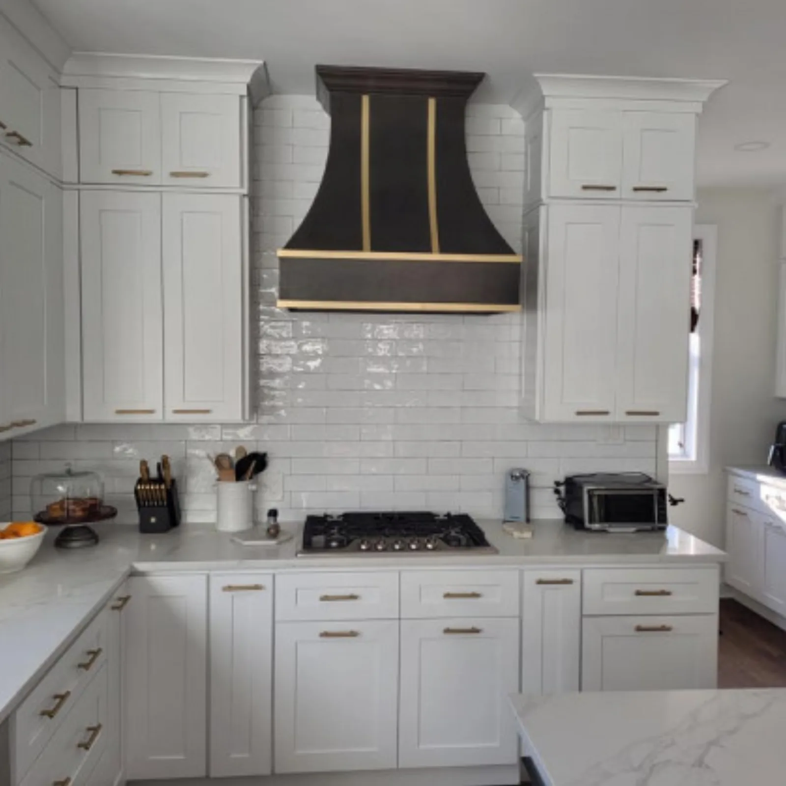 White kitchen with gold hardware and a custom range hood