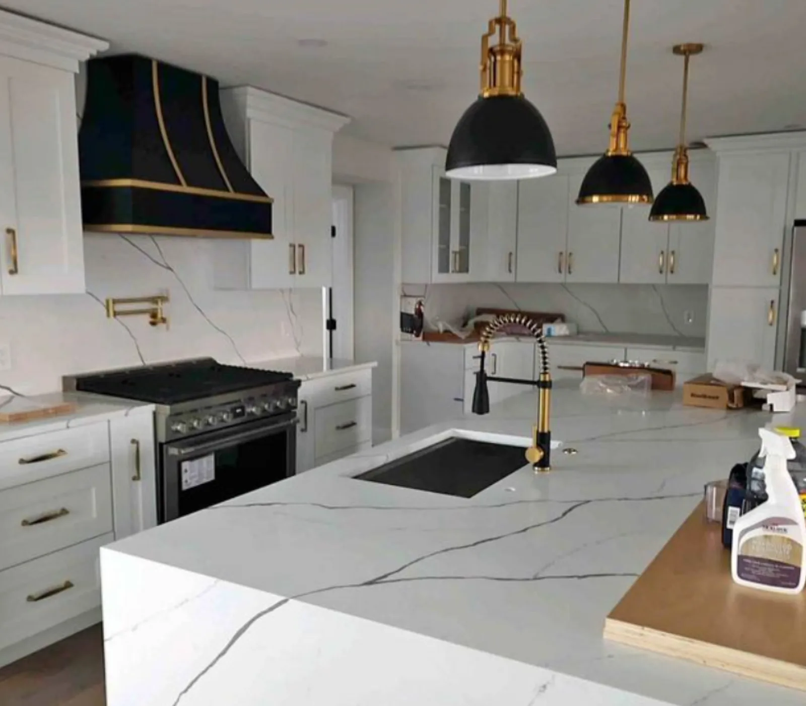 White kitchen with a marble island and a pot filler at the range