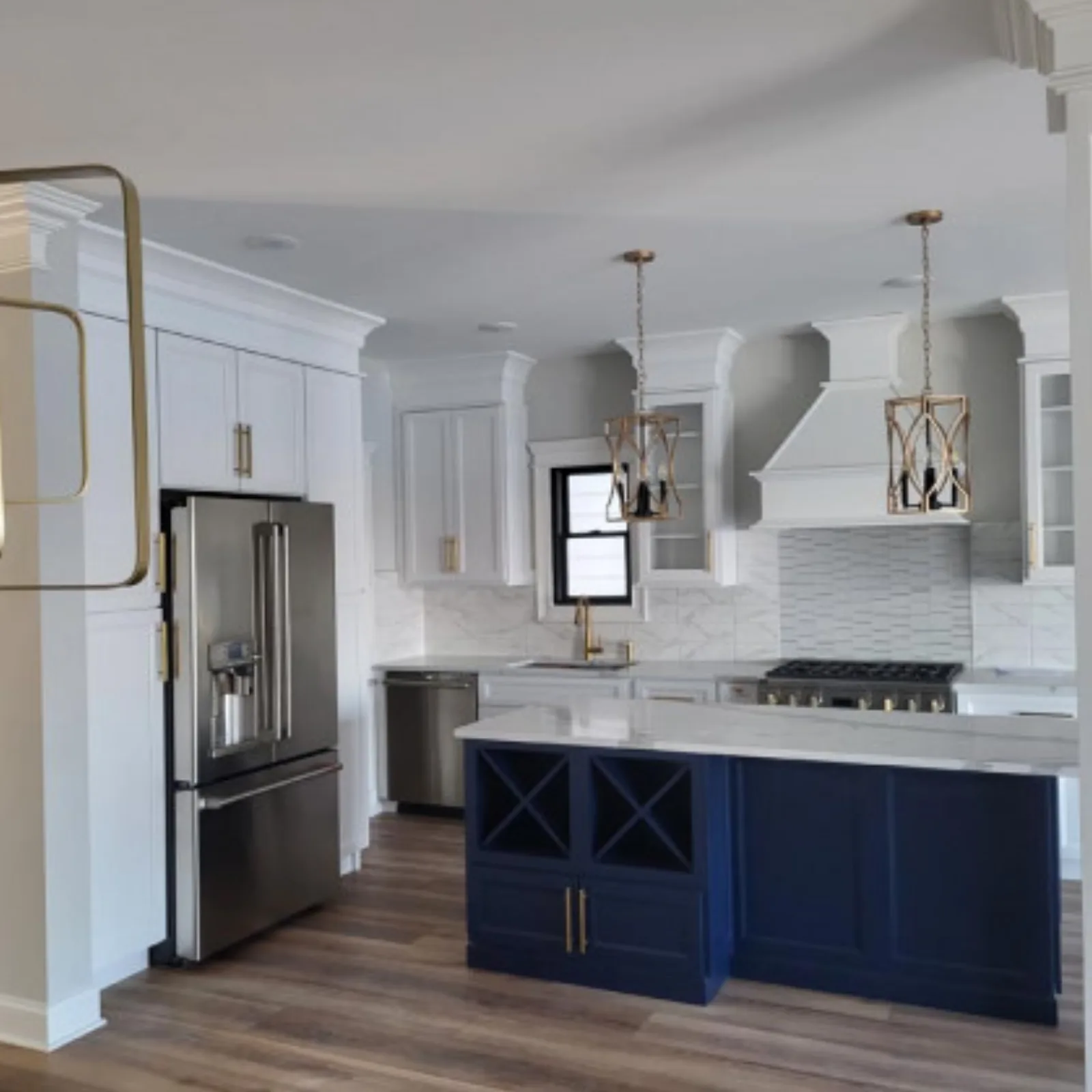 White kitchen with a navy island and brushed gold hardware