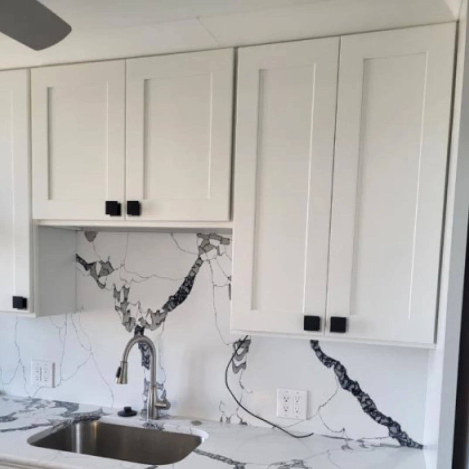 White shaker cabinets with a veined stone backsplash