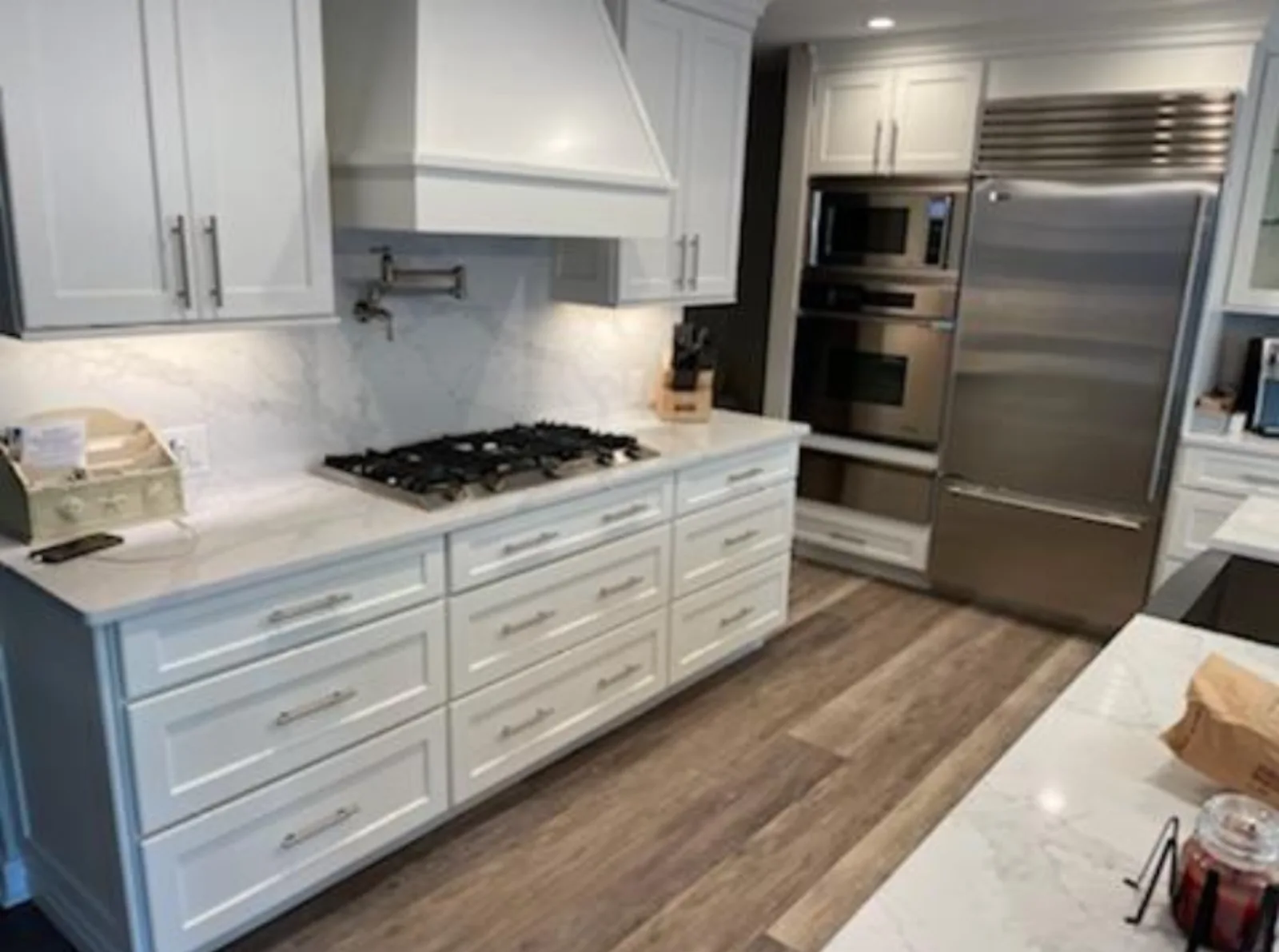 White shaker kitchen with wide plank wood flooring