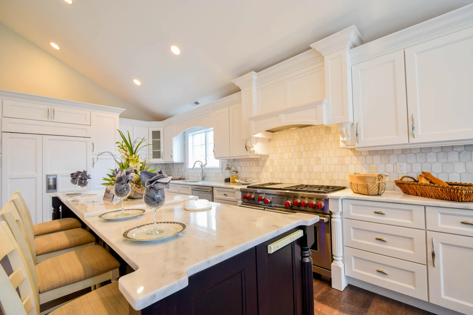 White kitchen under a vaulted ceiling with a marble island
