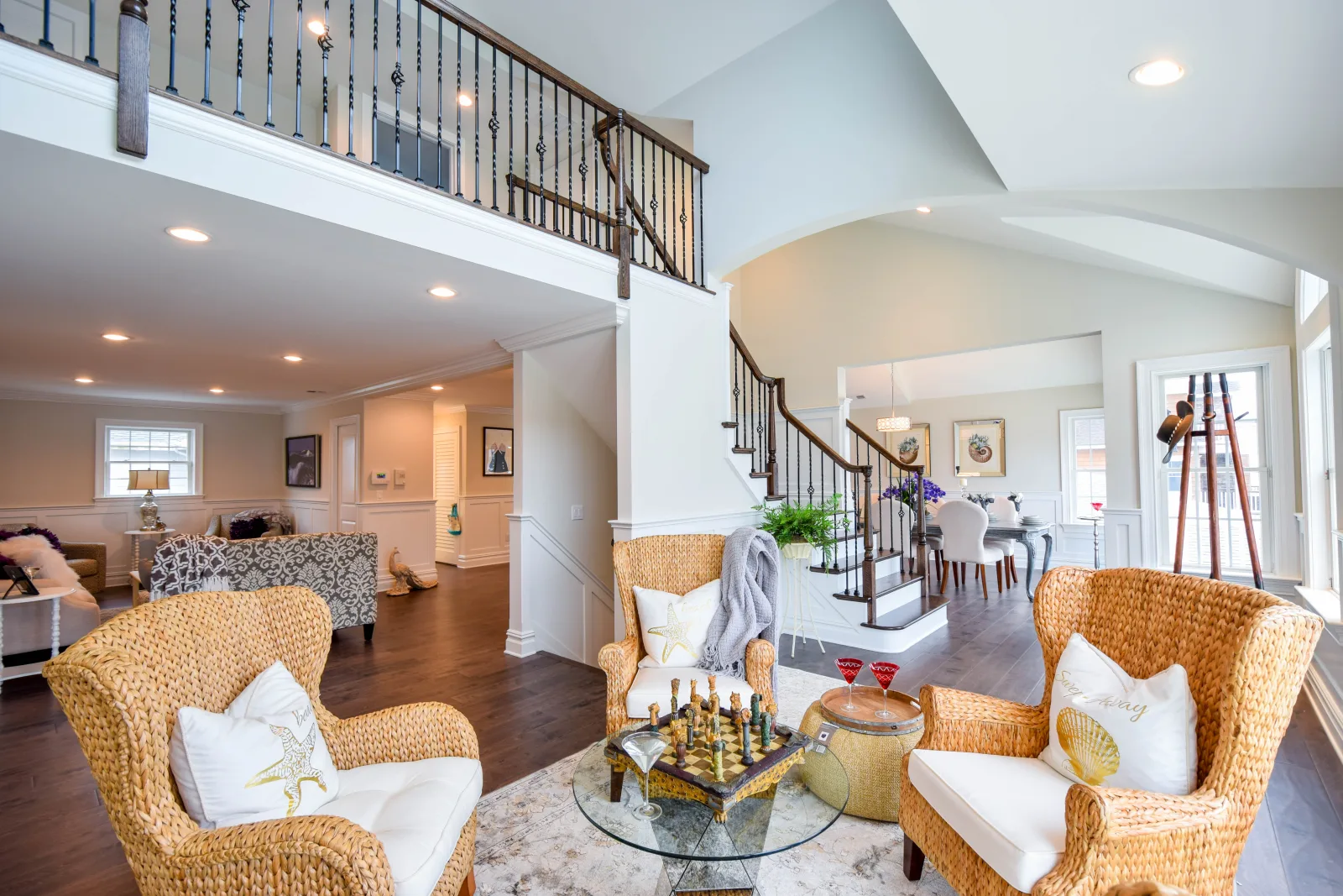 Two story living room with wicker armchairs and a curved oak staircase