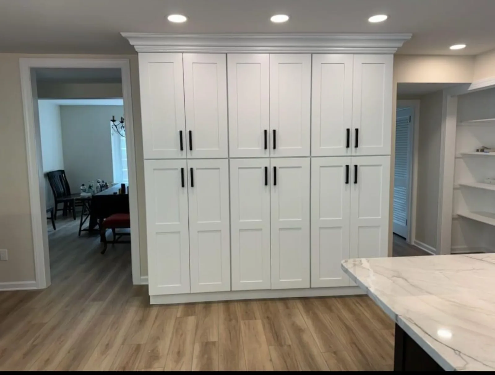 Pantry wall of tall white cabinets with black hardware